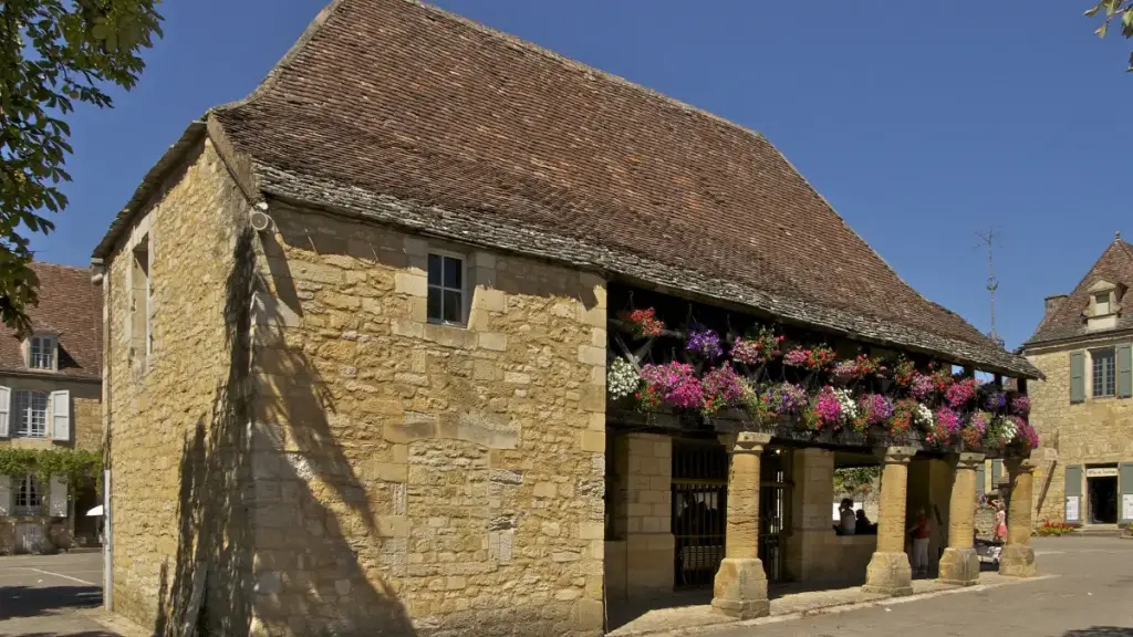Halle en pierre fleurie sur la place de la Halle, point de départ pour visiter Domme