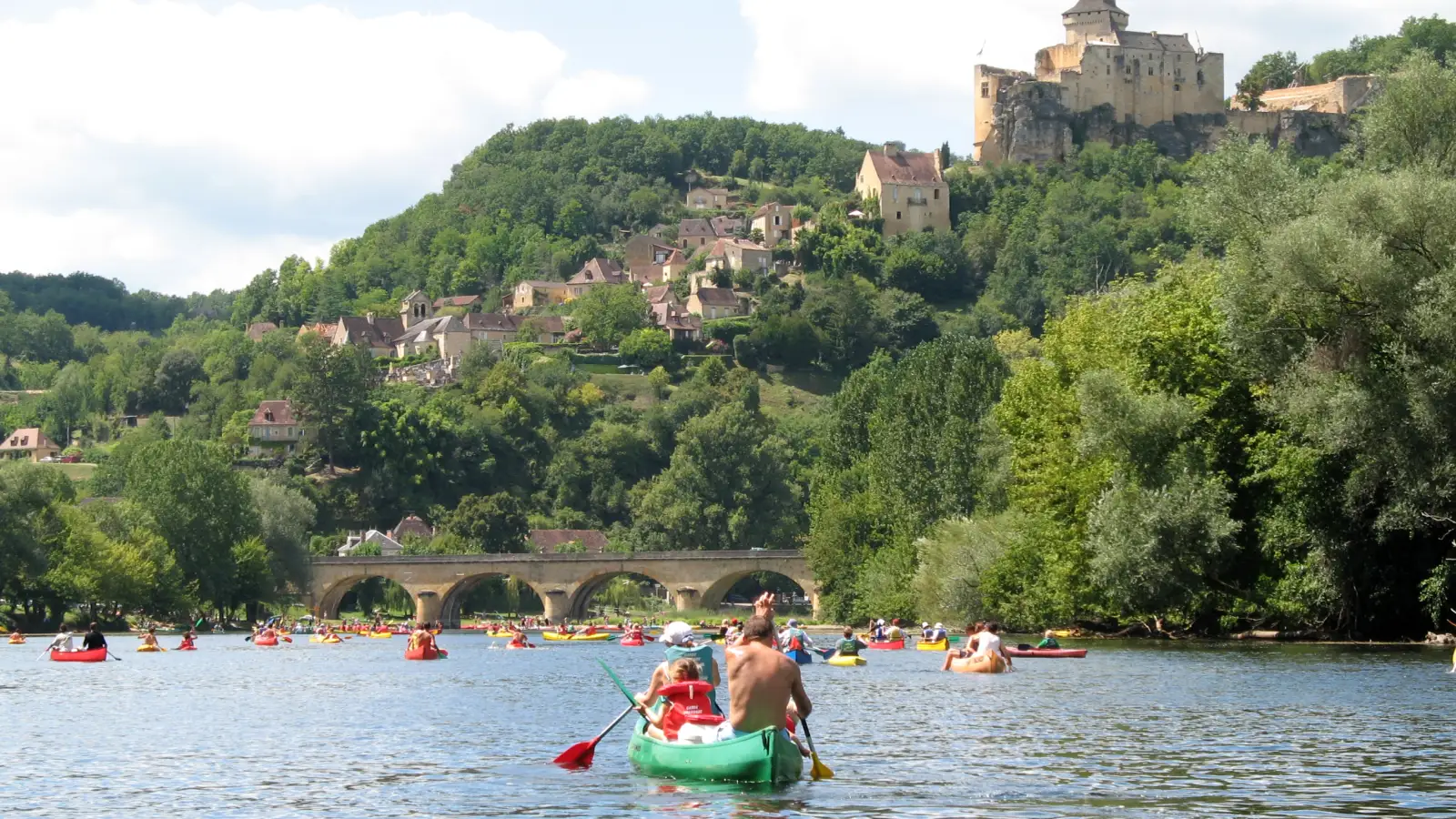 Château de Castelnaud dominant la Dordogne, avec des canoës sur la rivière